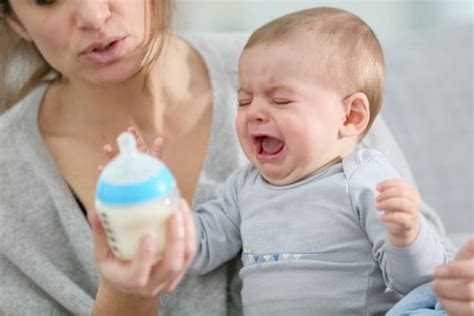 Bambino che piange rifiutando il biberon