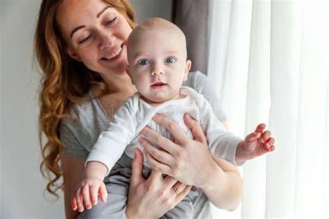Famiglia omosessuale che tiene in braccio un neonato, con una donna anziana sorridente sullo sfondo