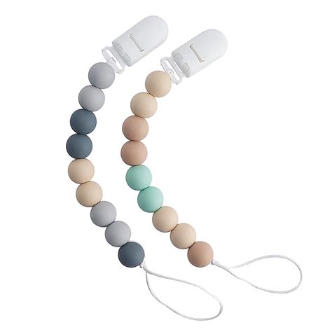 Parent attaching silicone pacifier holder to baby clothes