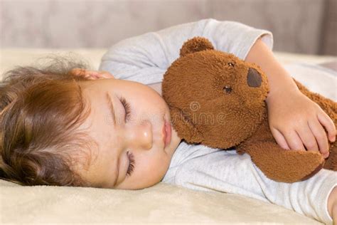 Un bambino che dorme serenamente abbracciato a un peluche