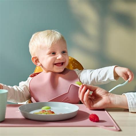Un bambino che indossa un bavaglino in silicone con tasca raccogli-cibo