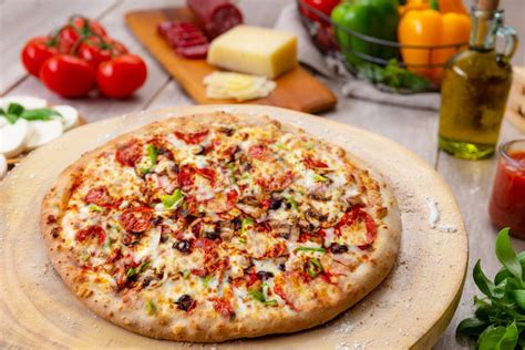 Una tavola imbandita con pizza fatta in casa appena sfornata, circondata da ingredienti freschi come pomodori, basilico e mozzarella, evocando un'atmosfera familiare.