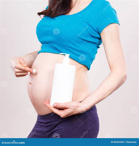 Donna incinta che applica olio sulla pancia