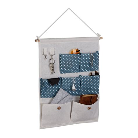 Pannello organizer in stoffa appeso su una parete della cameretta con varie tasche piene di materiale scolastico