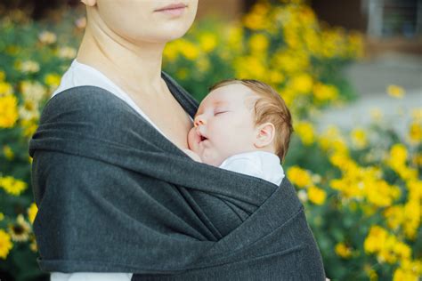 Genitore che pratica babywearing con fascia
