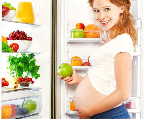 Donna incinta che sceglie tra frutta e verdura o cibi meno salutari