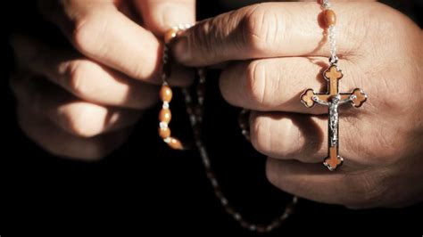 Una corona del Rosario tra le mani in preghiera