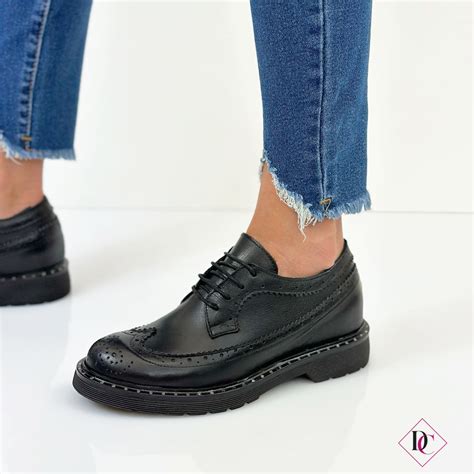 Modella che indossa un paio di scarpe stringate inglesine bianche eleganti abbinate a un outfit autunnale