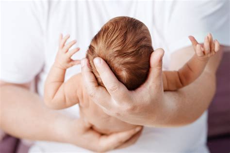 Mani di genitore che applicano olio delicatamente sulla testa di un bambino
