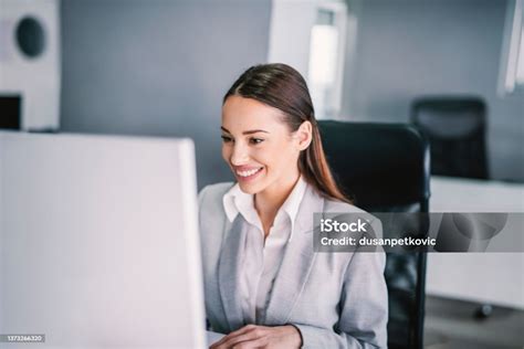 Donna incinta in ufficio che sorride al computer