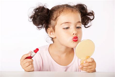 Bambina che si trucca davanti a uno specchio
