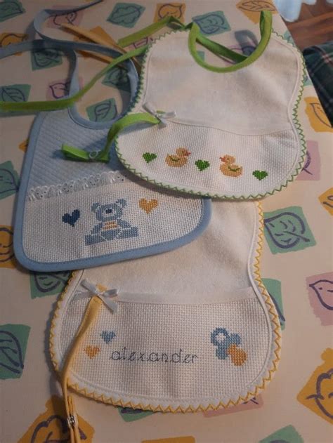 Manine di bambino che toccano un bavaglino ricamato a punto croce