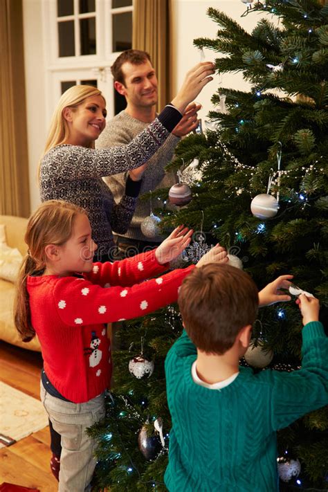 famiglia che decora insieme l'albero di natale in salotto