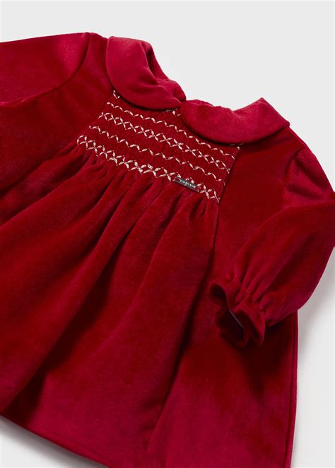 Bimba che indossa un elegante abito natalizio in velluto rosso con dettagli in pizzo