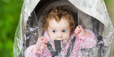 Bambino felice in passeggino con parapioggia