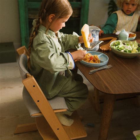 Bambino seduto a tavola che cerca di afferrare il cibo dal piatto dei genitori