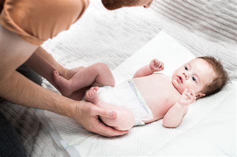 Un genitore che insegna al bambino a infilarsi il pannolino a mutandina