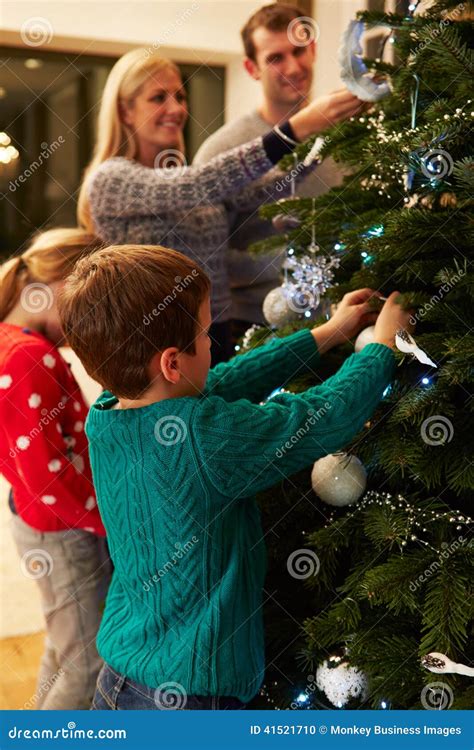 famiglia che decora insieme l'albero di Natale in un salotto accogliente