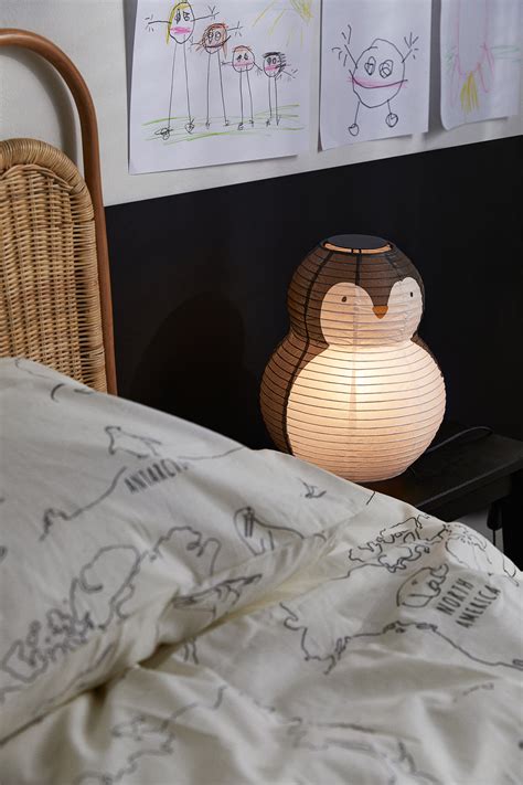 illustrazione stilizzata di una lampada a forma di pinguino Suavinex posizionata su un comodino in una camera da letto per bambini