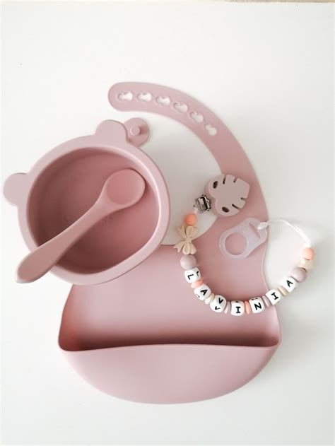 Un set di accessori per neonati con nomi incisi e colori pastello disposti in modo elegante