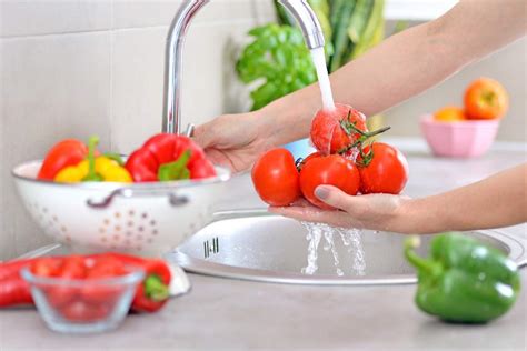 Donna incinta che lava le verdure sotto acqua corrente