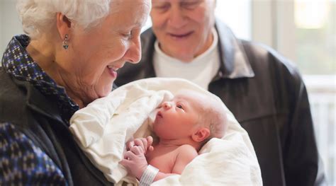 A happy family welcoming a new baby, with grandparents and relatives looking on with joy