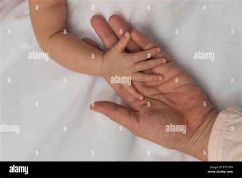 A mother holding her newborn baby's tiny hand