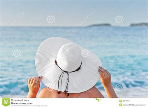 Donna incinta che prende il sole in sicurezza, con cappello e pareo