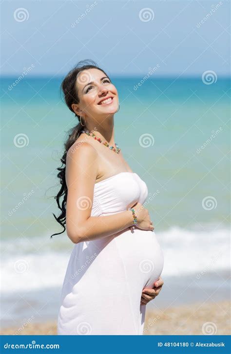 Donna incinta sorridente in bikini premaman sulla spiaggia