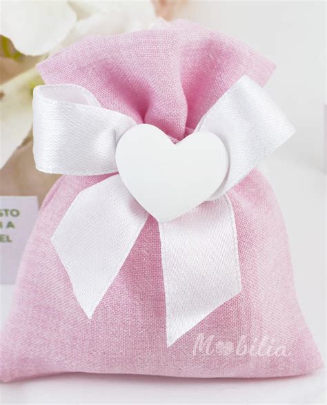 Dettaglio di sacchetto nascita in cotone rosa con fiocco in raso bianco e gessetto a forma di rosa