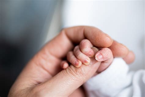 Mano di un adulto che stringe la mano di un neonato