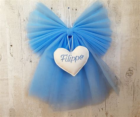 Composizione di materiali per fiocco nascita: tulle azzurro, nastri di raso, ovatta, cartoncino e decorazioni in legno