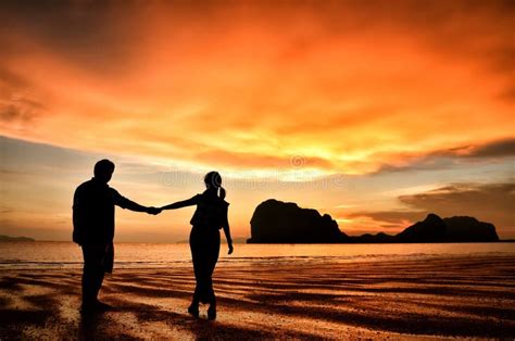 coppia che si tiene per mano guardando il tramonto