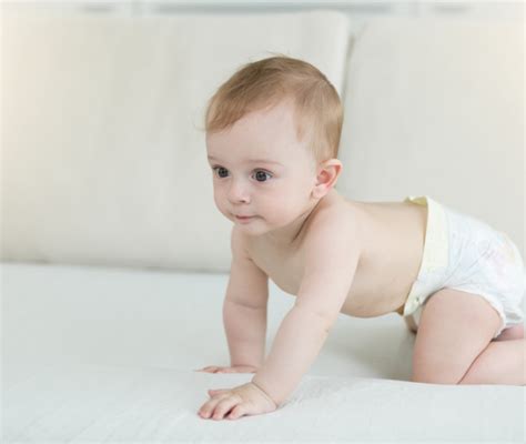 bambino di 10 mesi che esplora un armadio basso sicuro con utensili di legno