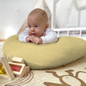 Bambino che gioca in posizione tummy time con il supporto di un cuscino allattamento
