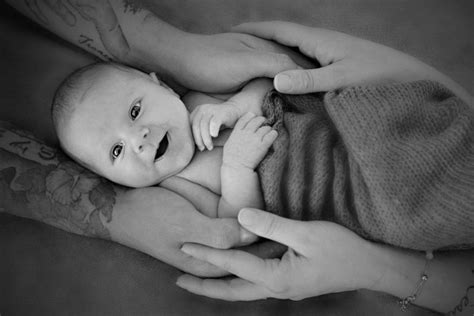 Un neonato avvolto in una coperta tra le mani dei genitori