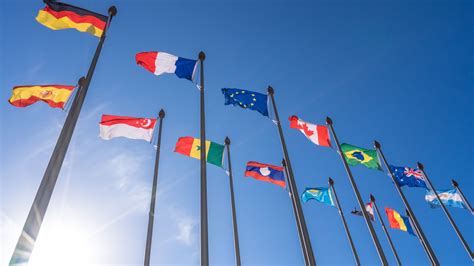 bandiere internazionali e documenti ufficiali che si intrecciano, a simboleggiare la cooperazione internazionale