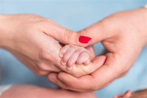 Mani di genitori che stringono la manina del neonato