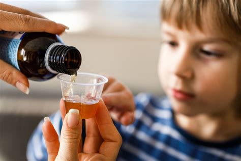 Bambino che riceve uno sciroppo da un genitore
