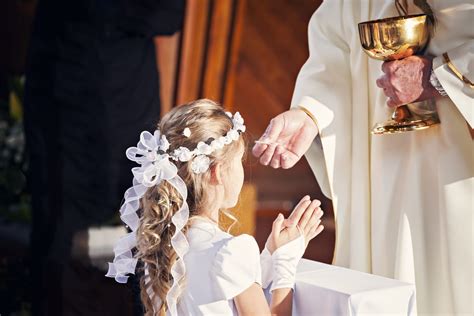 Bambino e bambina che ricevono la Prima Comunione con simboli religiosi