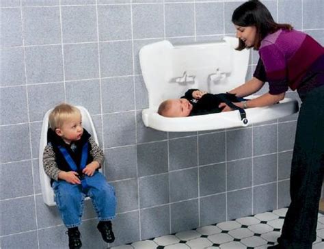 Bambino che viene cambiato sul fasciatoi a muro in un bagno pubblico