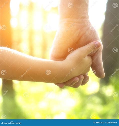 Mano di adulto che tiene la mano di un bambino, simbolo di nuova vita e speranza