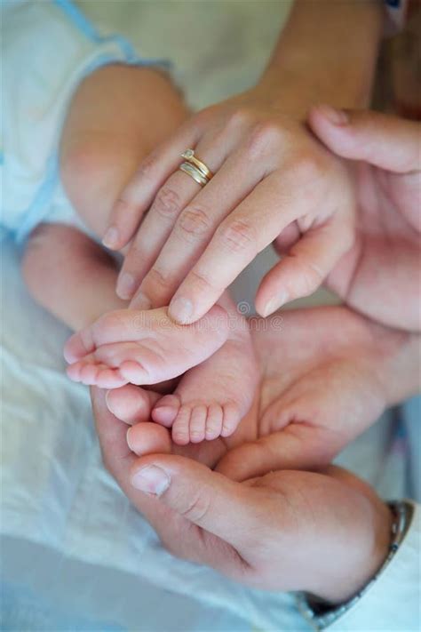 Foto delle mani dei genitori che tengono i piedini delle gemelle