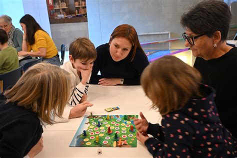 Bambini di 5 anni seduti attorno a un tavolo intenti a giocare con un gioco da tavolo colorato