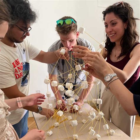 Ragazzi impegnati in un gioco di costruzione di torri con spaghetti e marshmallow