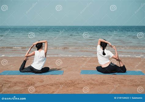 Genitori che praticano yoga sulla spiaggia al tramonto