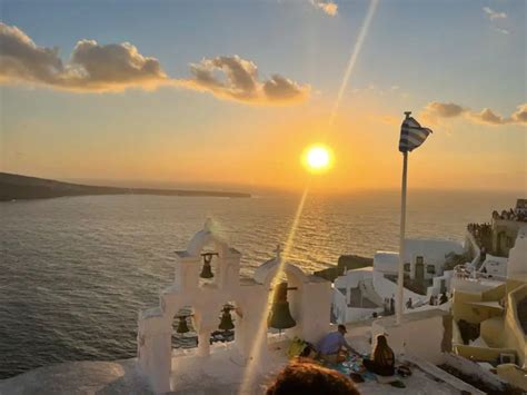 Coppia con bambino che ammira il tramonto a Santorini