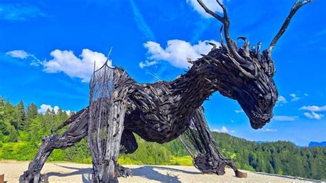 una scultura in legno di drago lungo un sentiero boschivo