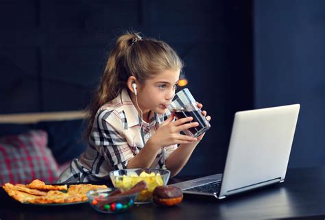 Bambino sedentario davanti a tablet con cibo spazzatura