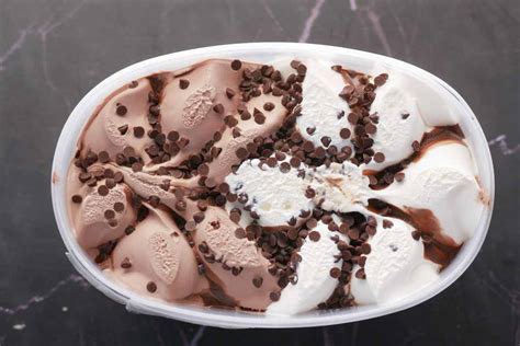 Vetrina di una gelateria con vaschette di gelato decorate con frutta fresca